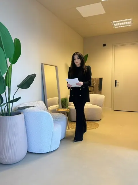 Joyce in de lichte lounge van haar studio met planten en bouclé-stoelen